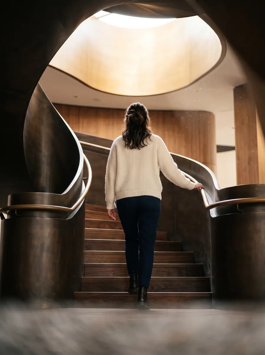 Eine Person steigt eine Wendeltreppe aus Bronze und Holz hinauf zum Licht